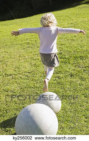 Rear view of a girl jumping from a stone View Large Photo Image Stock Image - Rear view of a girl jumping from a stone. Fotosearch