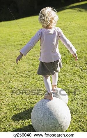 Rear view of a girl walking on round stones View Large Photo Image Stock Image - Rear view of a girl walking on round stones. Fotosearch