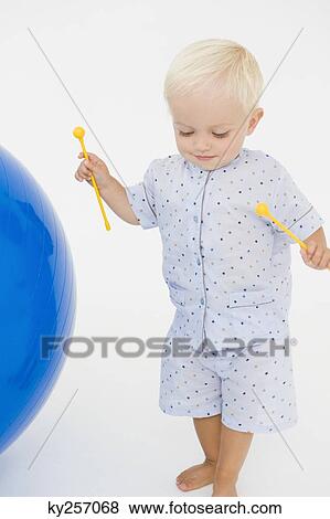 Baby boy holding xylophone mallets and standing near a fitness ball View Large Photo Image Stock Photo - Baby boy holding xylophone mallets and standing near a fitness ball. Fotosearch