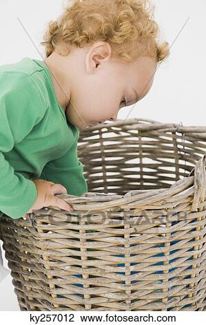 Stock Image - Baby boy looking into a wicker basket. Fotosearch
