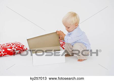Stock Image - Baby boy opening a box. Fotosearch