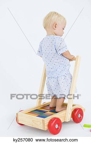 Stock Image - Baby boy playing with a push cart. Fotosearch
