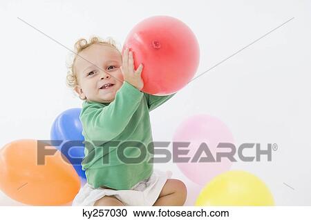 Stock Image - Baby boy playing with balloons. Fotosearch