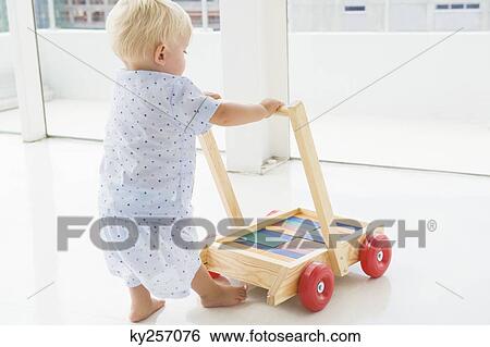 Baby boy pushing a cart View Large Photo Image Stock Photograph - Baby boy pushing a cart. Fotosearch