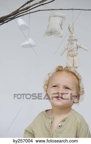 Close-up of a baby boy with toys hanging from sticks above him View Large Photo Image Picture - Close-up of a baby boy with toys hanging from sticks above him. Fotosearch