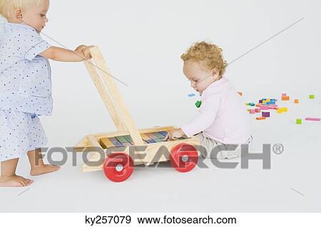 Two baby boys playing with a push cart View Large Photo Image Stock Photo - Two baby boys playing with a push cart. Fotosearch