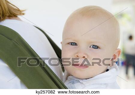Stock Image - Woman carrying her son in a baby carrier. Fotosearch