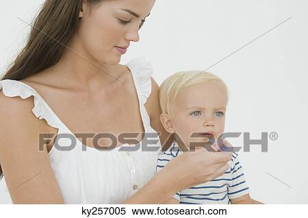 Woman feeding her son View Large Photo Image Stock Photography - Woman feeding her son. Fotosearch