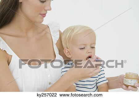 Stock Image - Woman feeding honey to her son. Fotosearch