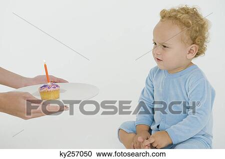 Woman offering a cupcake to her son on his first birthday View Large Photo Image Stock Image - Woman offering a cupcake to her son on his first birthday. Fotosearch