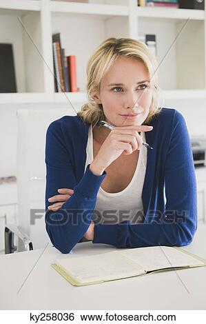 Businesswoman holding a pen and thinking View Large Photo Image Stock Photograph - Businesswoman holding a pen and thinking. Fotosearch