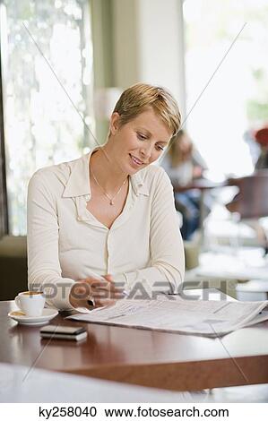 Businesswoman sitting in a restaurant and reading a financial newspaper View Large Photo Image Stock Image - Businesswoman sitting in a restaurant and reading a financial newspaper. Fotosearch