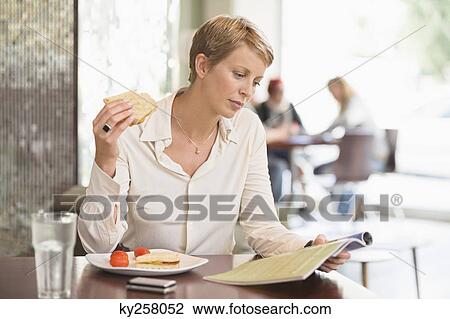Businesswoman sitting in a restaurant and reading a magazine View Large Photo Image Stock Image - Businesswoman sitting in a restaurant and reading a magazine. Fotosearch