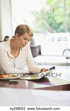 Businesswoman sitting in a restaurant and reading a magazine View Large Photo Image Stock Image - Businesswoman sitting in a restaurant and reading a magazine. Fotosearch