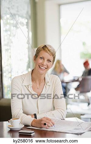 Businesswoman sitting in a restaurant and reading a financial newspaper View Large Photo Image Stock Photograph - Businesswoman sitting in a restaurant and reading a financial newspaper. Fotosearch