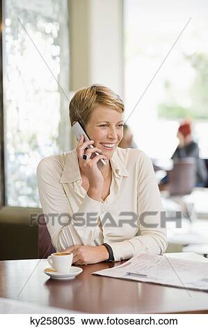 Businesswoman sitting in a restaurant and talking on a mobile phone View Large Photo Image Stock Photography - Businesswoman sitting in a restaurant and talking on a mobile phone. Fotosearch