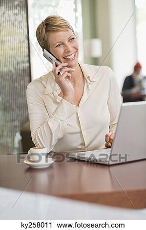 Businesswoman talking on a mobile phone in a restaurant View Large Photo Image Stock Image - Businesswoman talking on a mobile phone in a restaurant. Fotosearch