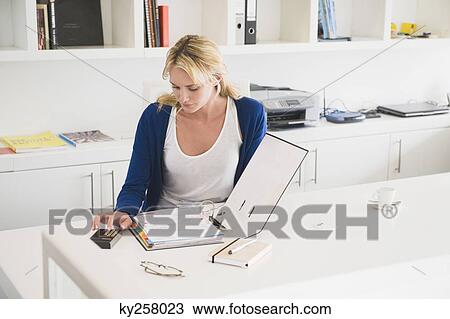 Stock Image - Businesswoman using a calculator. Fotosearch