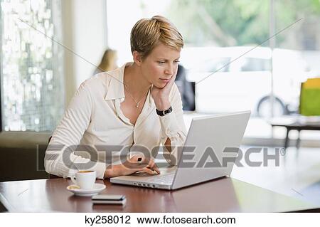 Businesswoman working on a laptop in a restaurant View Large Photo Image Stock Image - Businesswoman working on a laptop in a restaurant. Fotosearch