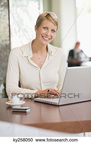 Businesswoman working on a laptop in a restaurant View Large Photo Image Stock Image - Businesswoman working on a laptop in a restaurant. Fotosearch