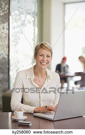 Stock Image - Businesswoman working on a laptop in a restaurant. Fotosearch