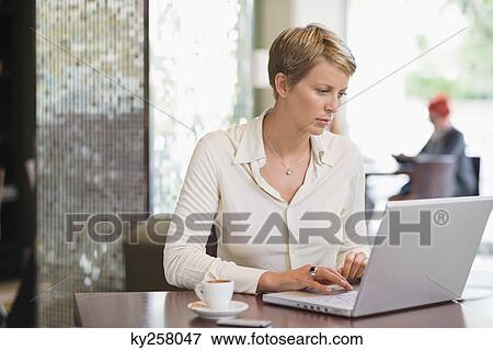 Stock Photo - Businesswoman working on a laptop in a restaurant. Fotosearch