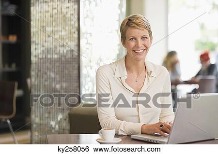 Businesswoman working on a laptop in a restaurant View Large Photo Image Stock Photograph - Businesswoman working on a laptop in a restaurant. Fotosearch