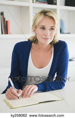 Stock Image - Businesswoman writing on a notepad. Fotosearch