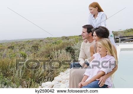 Family sitting at the poolside and admiring the view View Large Photo Image Stock Image - Family sitting at the poolside and admiring the view. Fotosearch