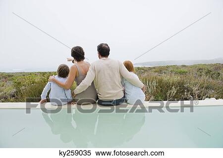 Stock Photography - Family sitting at the poolside. Fotosearch