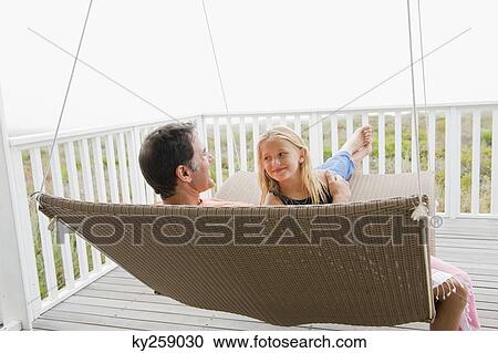 Girl sitting on a swing with her father View Large Photo Image Stock Image - Girl sitting on a swing with her father. Fotosearch