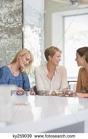 Stock Photo - Three women sitting in a restaurant. Fotosearch