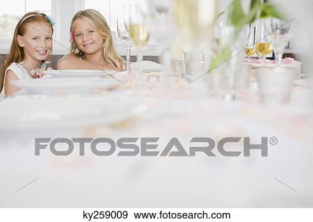 Two girls sitting at a dining table View Large Photo Image Stock Photo - Two girls sitting at a dining table. Fotosearch