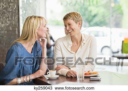 Two women sitting in a restaurant and smiling View Large Photo Image Stock Image - Two women sitting in a restaurant and smiling. Fotosearch