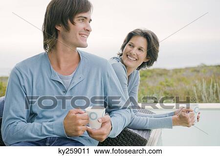Stock Image - Woman and her son drinking tea at the poolside. Fotosearch