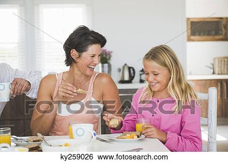 Woman having breakfast with her daughter at the dining table View Large Photo Image Stock Photograph - Woman having breakfast with her daughter at the dining table. Fotosearch