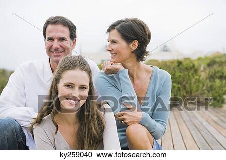 Woman sitting on a boardwalk with her parents View Large Photo Image Stock Image - Woman sitting on a boardwalk with her parents. Fotosearch