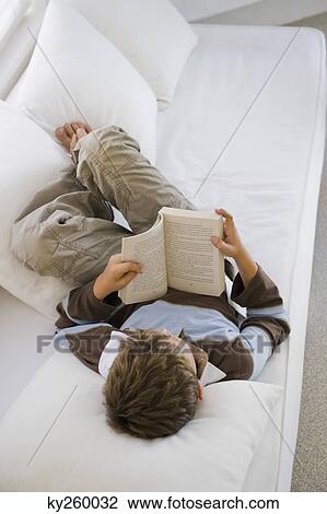 Boy lying on a couch and reading a book View Large Photo Image Stock Image - Boy lying on a couch and reading a book. Fotosearch