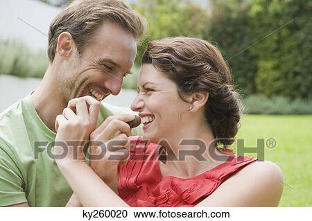 Couple feeding chocolates to each other and smiling View Large Photo Image Stock Image - Couple feeding chocolates to each other and smiling. Fotosearch