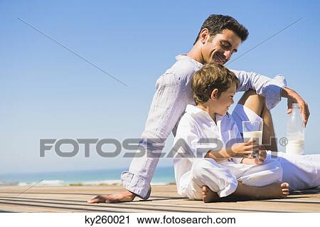 Man and his son drinking milk on the beach View Large Photo Image Stock Image - Man and his son drinking milk on the beach. Fotosearch