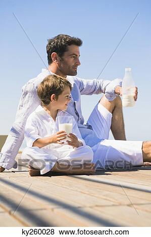 Man and his son drinking milk on the beach View Large Photo Image Stock Photo - Man and his son drinking milk on the beach. Fotosearch