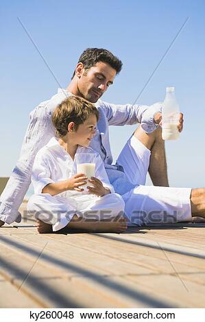 Man and his son drinking milk on the beach View Large Photo Image Stock Photo - Man and his son drinking milk on the beach. Fotosearch