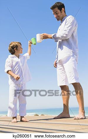 Man and his son toasting with coffee cups on the beach View Large Photo Image Stock Image - Man and his son toasting with coffee cups on the beach. Fotosearch