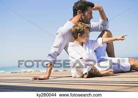 Picture - Man sitting on a boardwalk with his son. Fotosearch