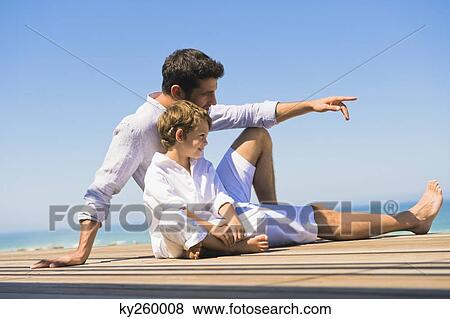 Man sitting on a boardwalk with his son View Large Photo Image Stock Photo - Man sitting on a boardwalk with his son. Fotosearch