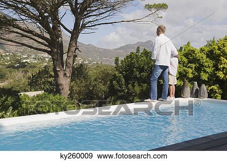 Man standing at the poolside with his son View Large Photo Image Stock Photo - Man standing at the poolside with his son. Fotosearch