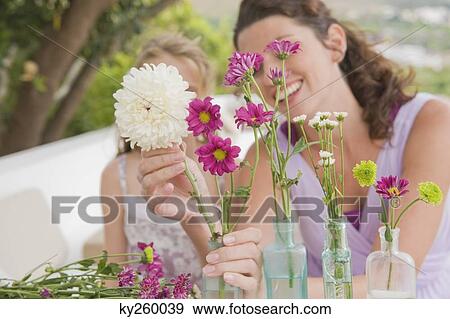 Woman with her daughter arranging flowers in a vase View Large Photo Image Stock Photo - Woman with her daughter arranging flowers in a vase. Fotosearch