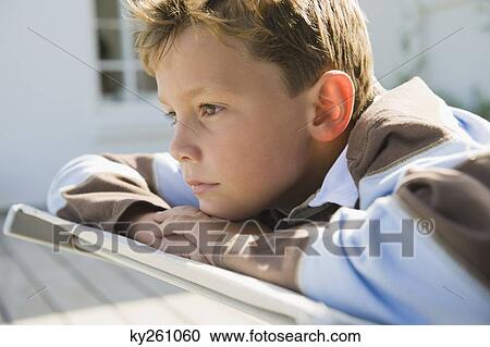 Stock Image - Boy resting on a deck chair. Fotosearch