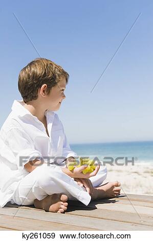 Boy sitting on a boardwalk and holding grapes View Large Photo Image Stock Photo - Boy sitting on a boardwalk and holding grapes. Fotosearch