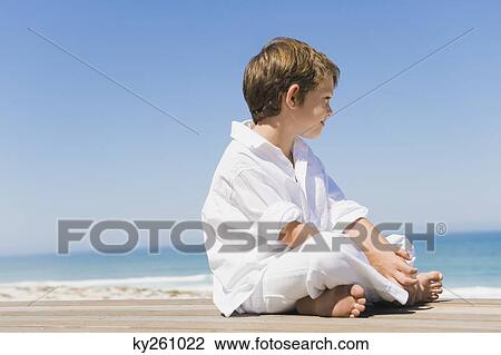 Boy sitting on a boardwalk on the beach View Large Photo Image Stock Image - Boy sitting on a boardwalk on the beach. Fotosearch